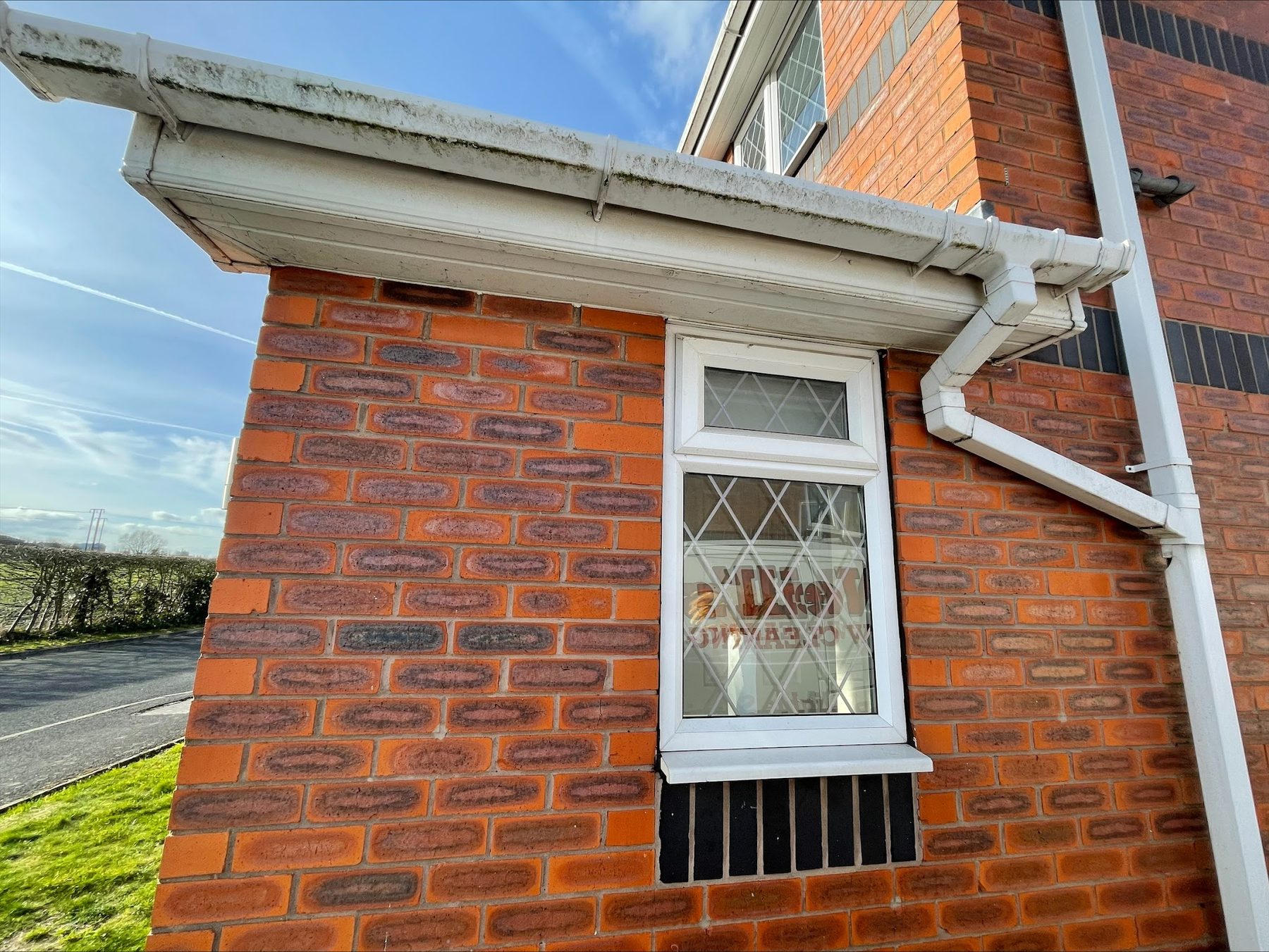 Bright white fascia board, gutter and downpipe on a red brick house