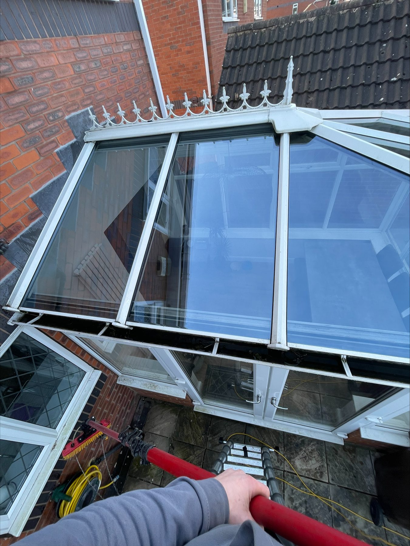 Cleaning a conservatory roof with a red water-fed pole