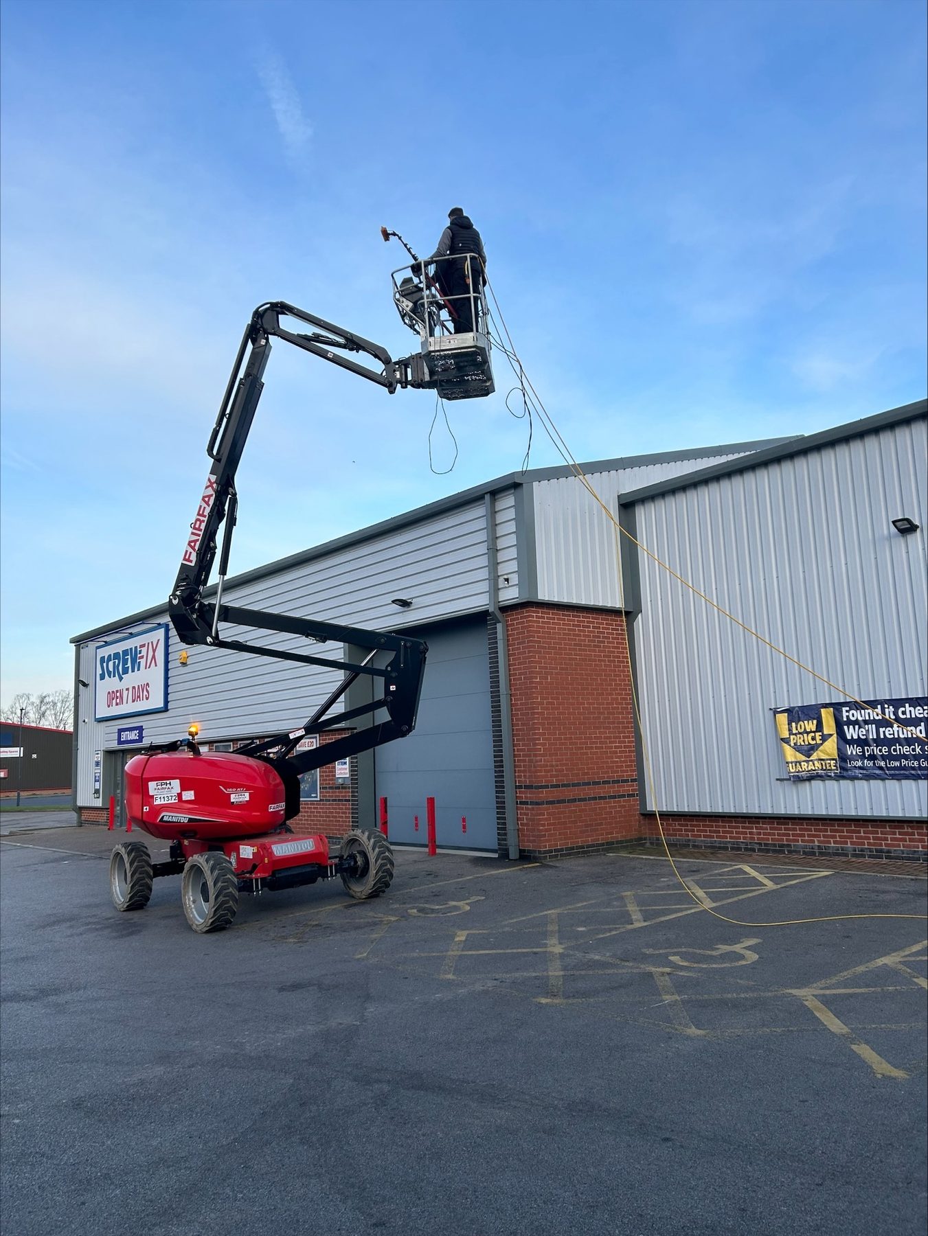 Working high up on the cladding of a trade unit from a cherry picker